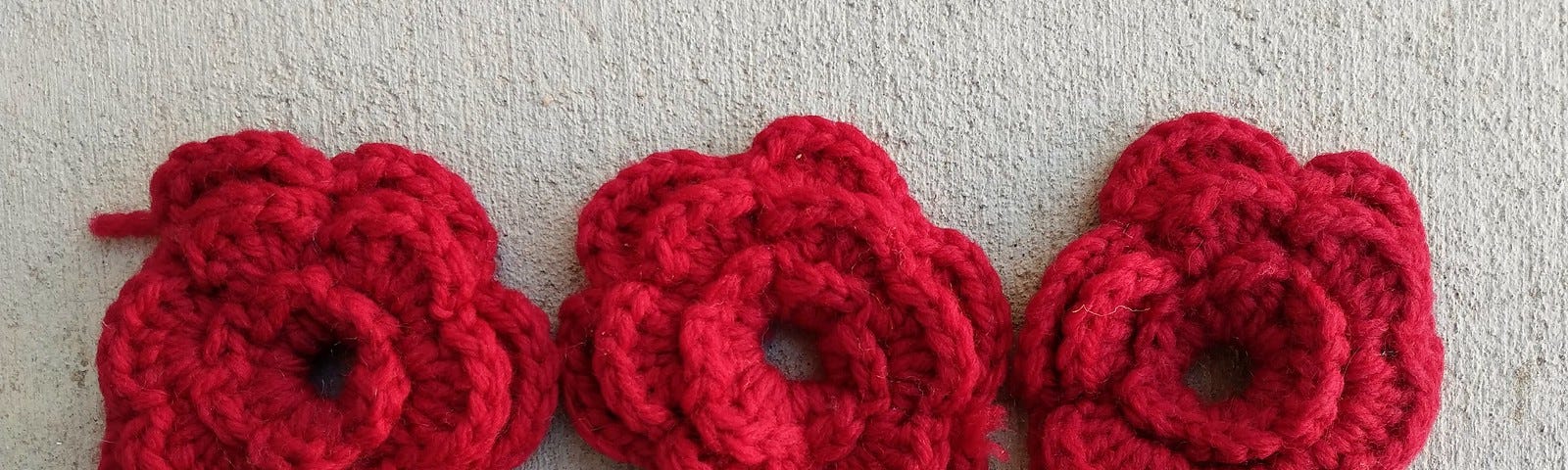 Three red crochet flowers