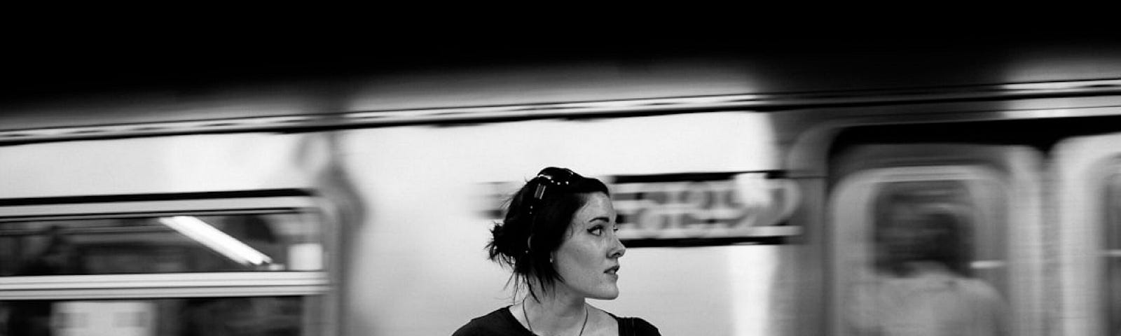 Annie Spratt took this black-and-white photo of a young woman standing on a subway platform looking to her left.