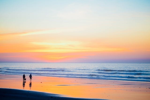 People walking near the shore, sunrise