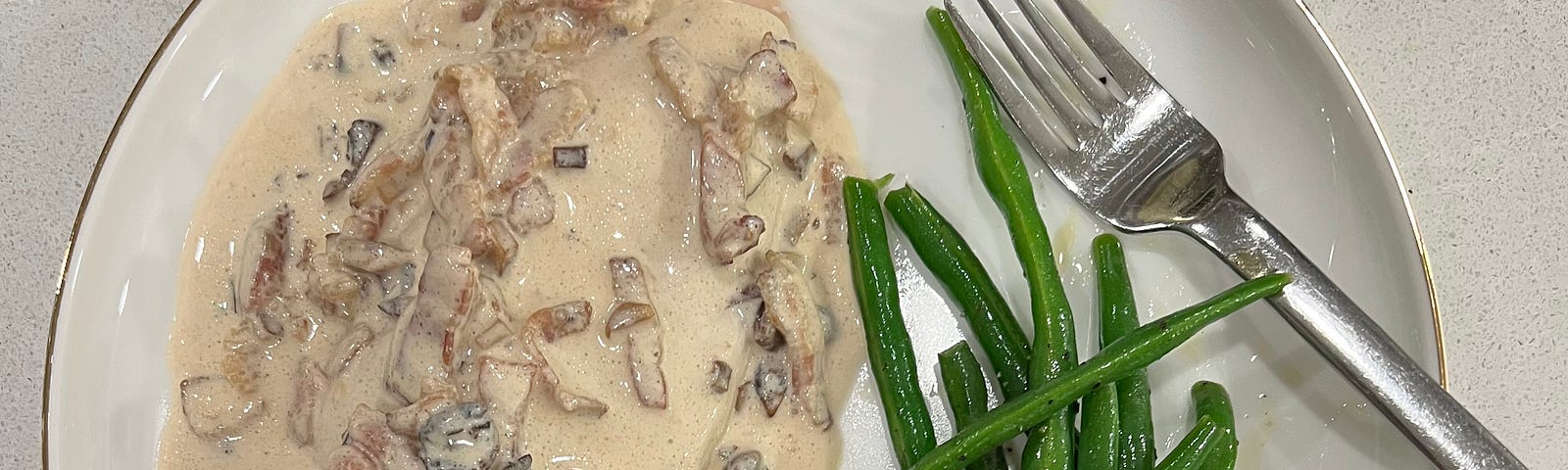 White china plate with chicken breast in creamy Bristol Bosci sauce