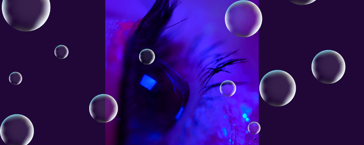 A close-up of a purple eye with bubbles over it.