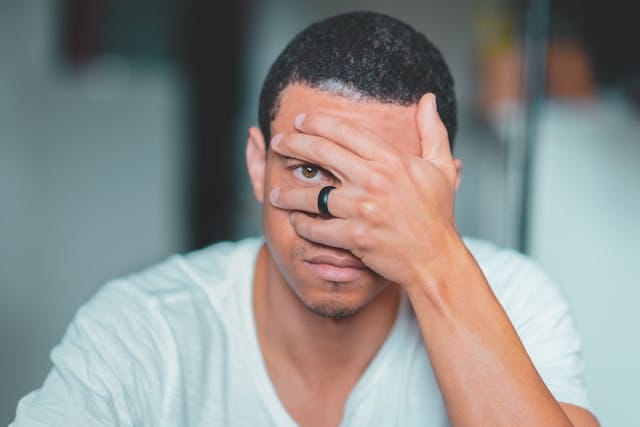 A man covering his face with his hand and taking a peek from between his fingers