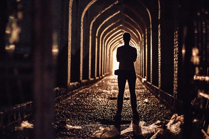 Silhouette of a person looking down the length of a tunnel, symbolizing the struggle and the rewards ahead.