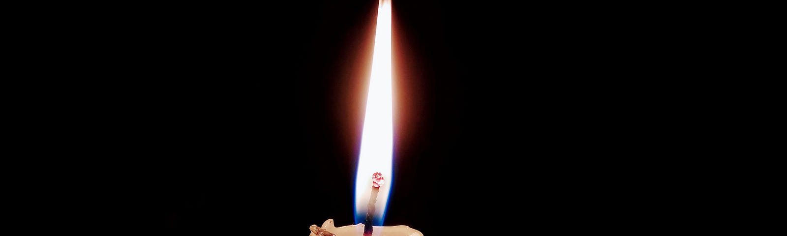 A candle burning against a dark background.