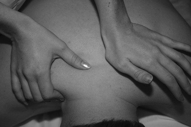 A woman giving a man a massage.