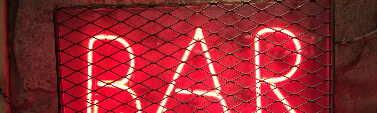Red neon sign that says bar under some chain metal