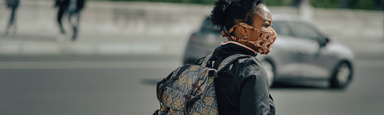 A Black woman sitting on a bike with a face mask on