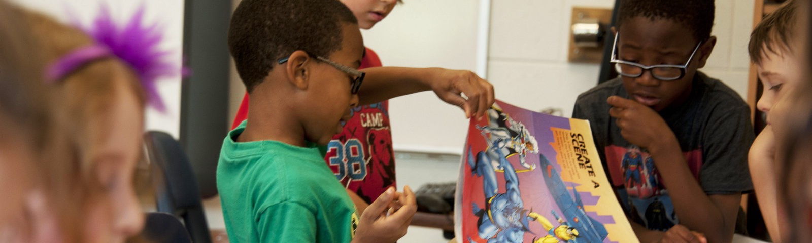 Three young kids flipping through a comic book at school