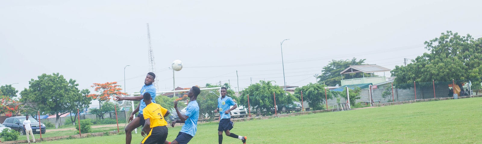 Four football players competing for a ball in the air