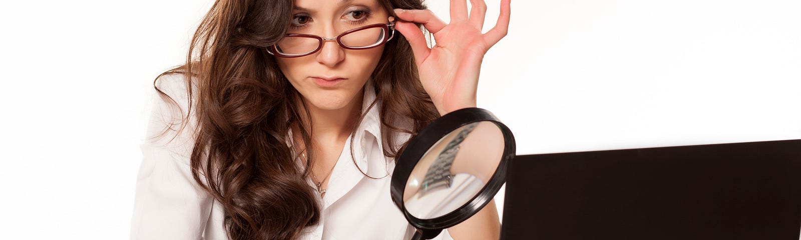 Woman with a magnifying glass looking at a computer (relationships, spying on partner, cheating)