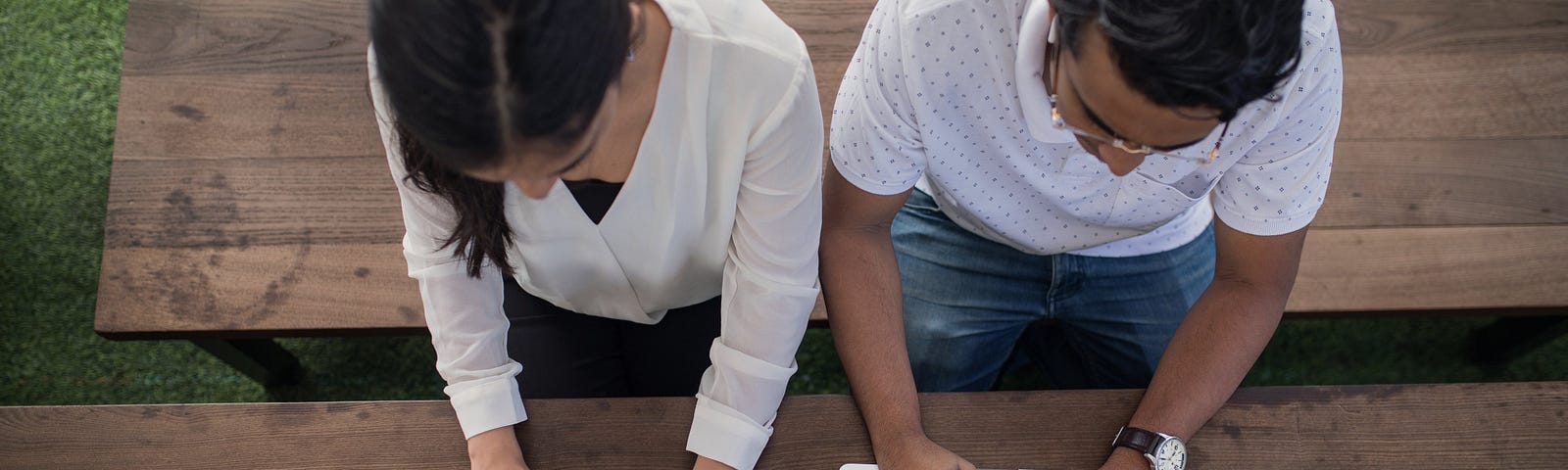 Two people on laptops sitting next to each other at a table