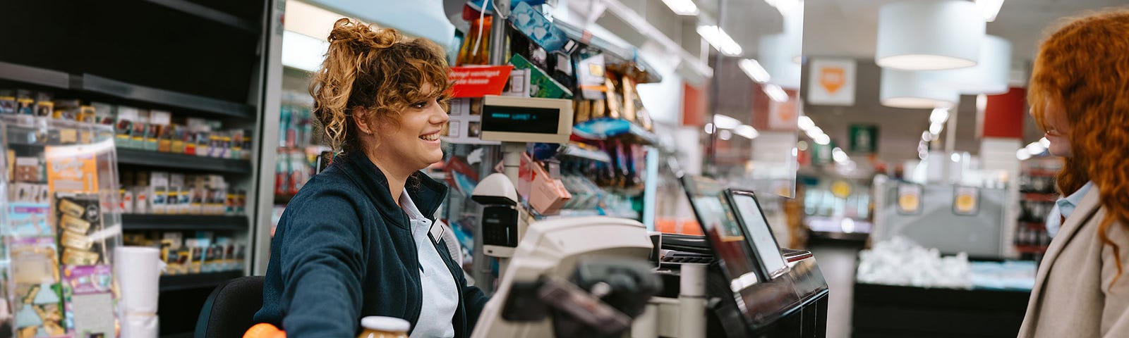 Cashier checking out customer while smiling at them