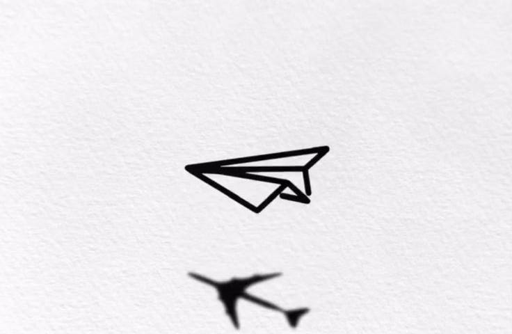 A drawing of a paper airplane with its shadow taking the form of a realistic plane