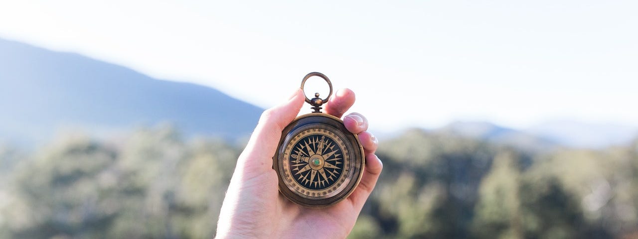A picture in the mountains of a hand holding a compass.