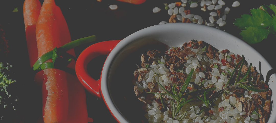 A festive bowl of food surrounded by orange carrots tied with green ribbons next to the word Pride.