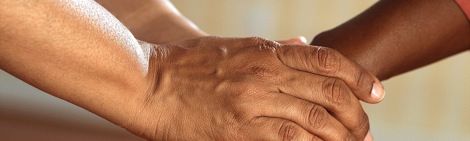 closeup of two peoples’ hands clasped lightly together in a way suggesting emotional closeness