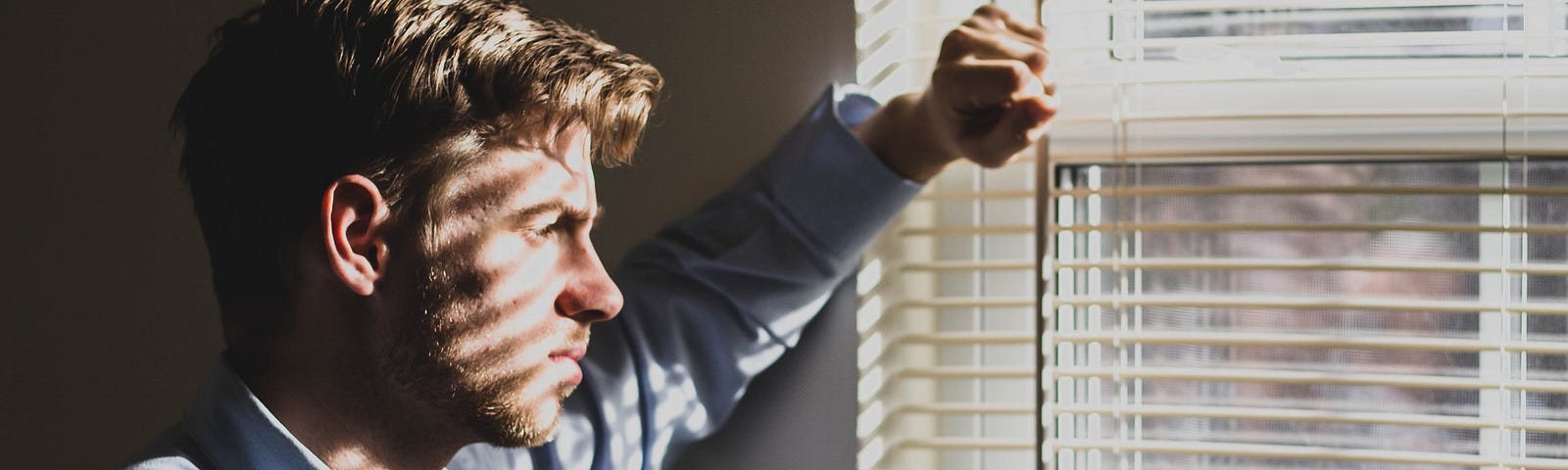 Man looking out the window who appears miserable