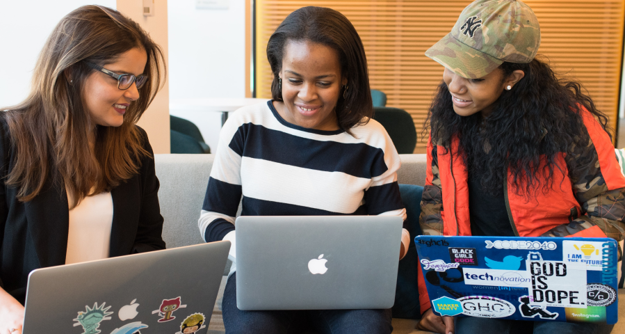Three young women with laptops working together.
