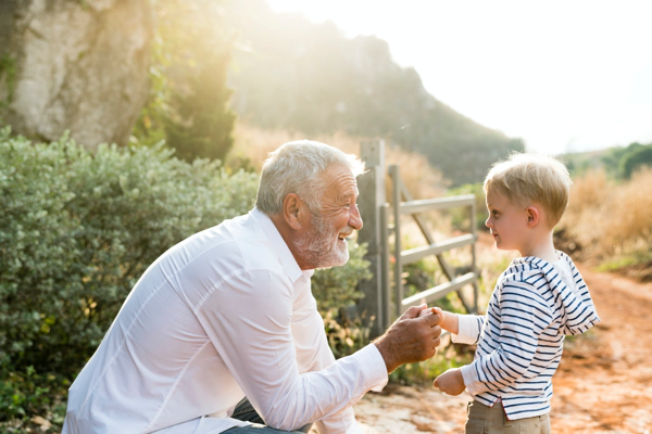 A grandfather shaking hands with his grandson — or perhaps handing something to him