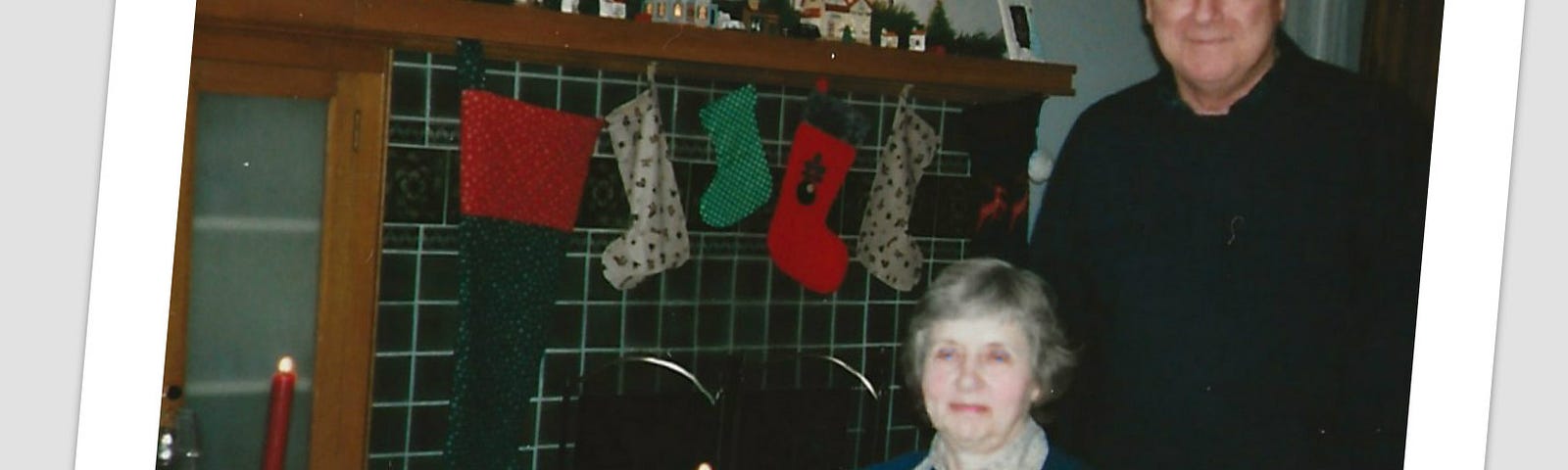 A man seats a woman at a table set with full soup bowls and decorated for Christmas.