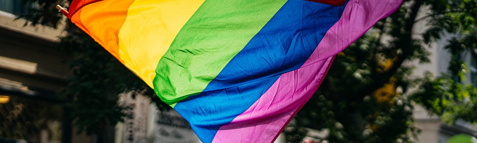 Pride flag being waved with two hands during a parade