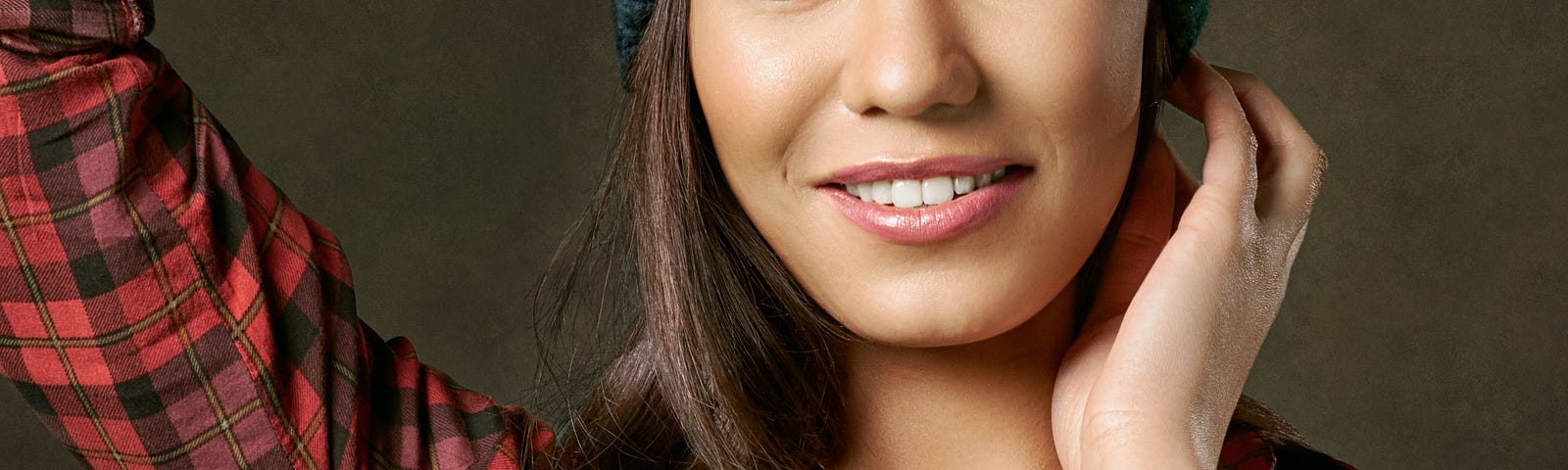 Smiling woman, tan complexion, beanie, flannel shirt