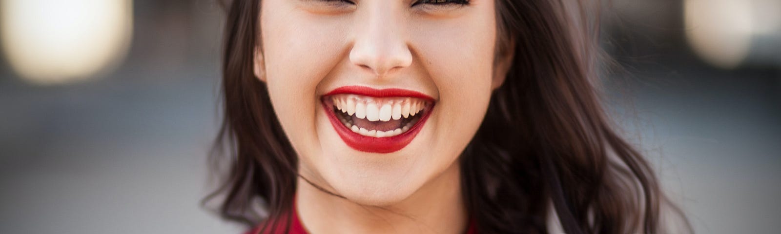 Long haired, brunette, Caucasian woman, wearing a long sleeve red pull-over smiling for the camera.