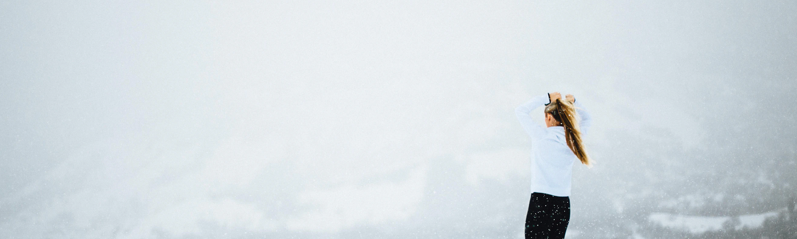 A woman standing in snow and looking out a snowy landscape.