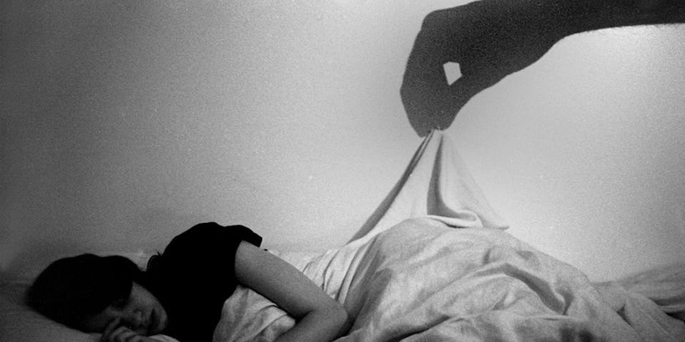 A victim of a narcissistic person hides in bed while a shadow pulls at their covers.