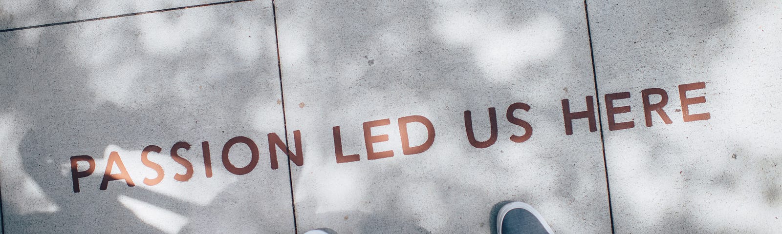 two sets of feet on a sidewalk in front of a phrase that says “passion led us here”