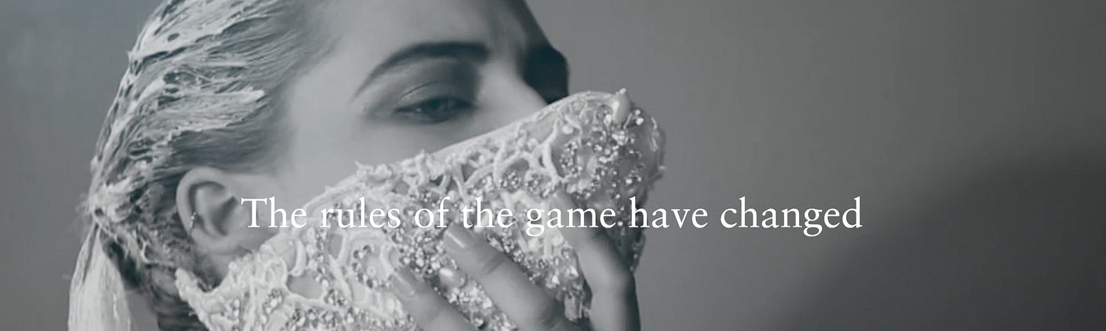 A woman holding fabric from her neck to over her mouth and nose. Above it says: The rules of the game have changed.