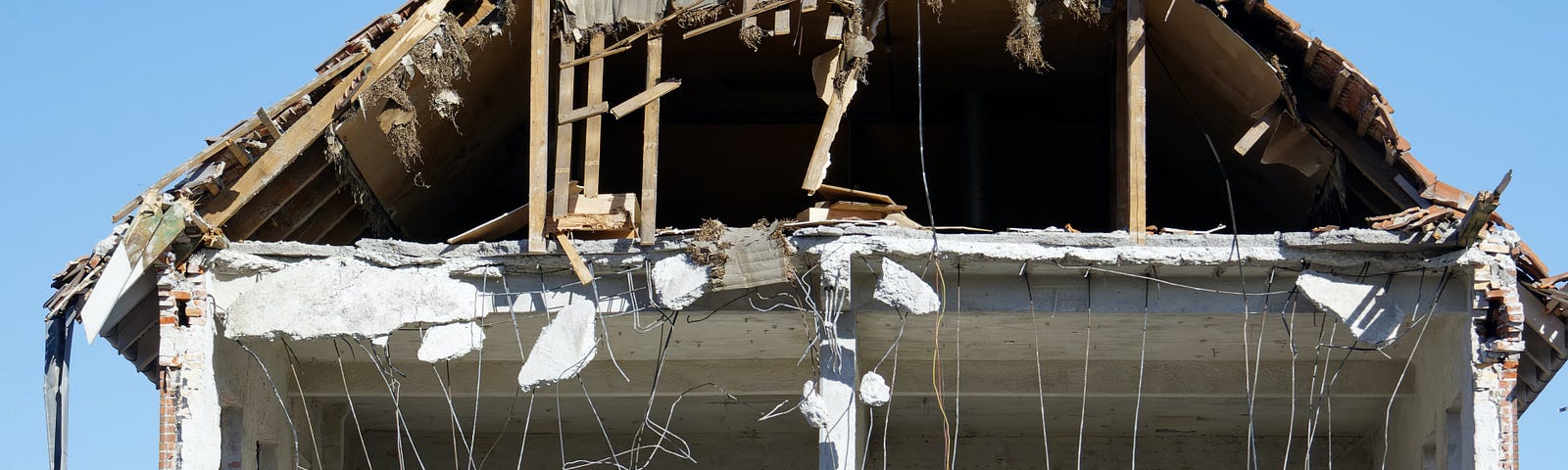 House with walls knocked out and wires dangling.