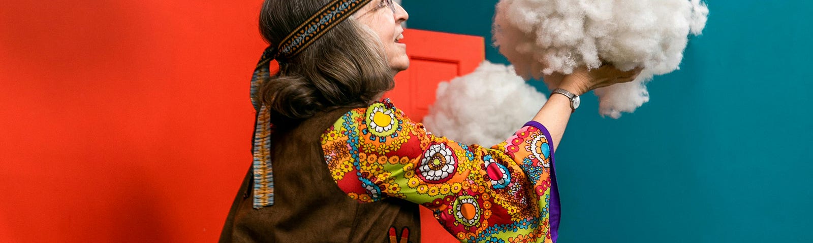 Older woman dressed in hippie clothes playing with a fake cloud in a garden. Peace. Older. Healthy.