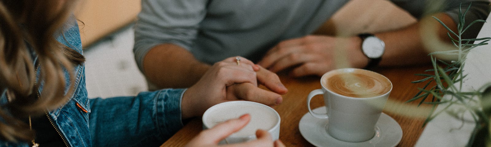 Photo of man and woman drinking coffee and holding hands.