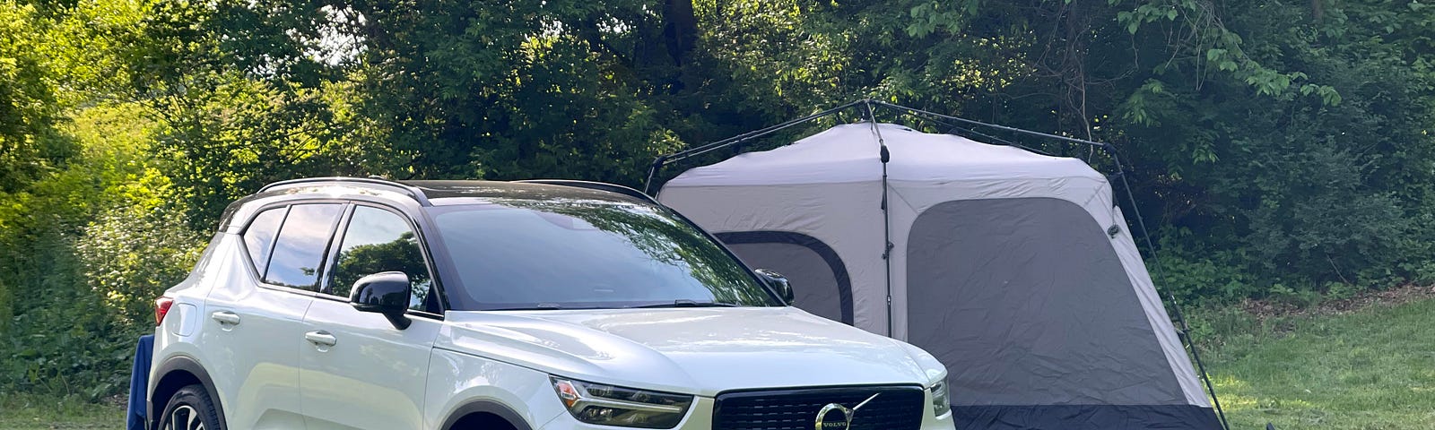 A Volvo SUV sitting adjacent to a tent outdoors.