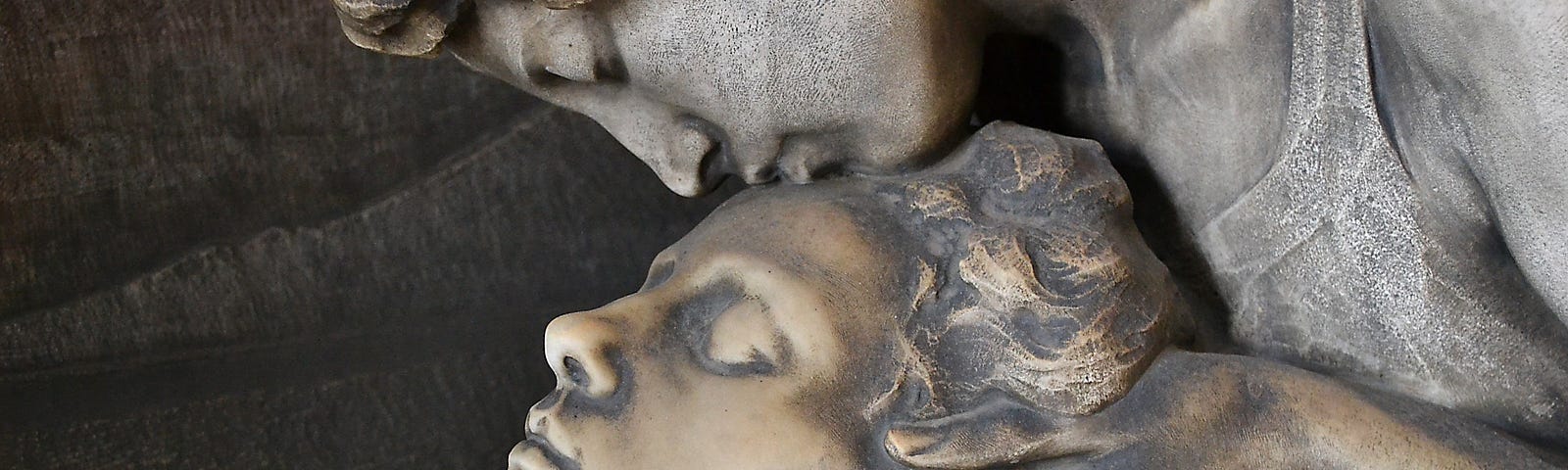 A statue of some kissing another on the forehead.