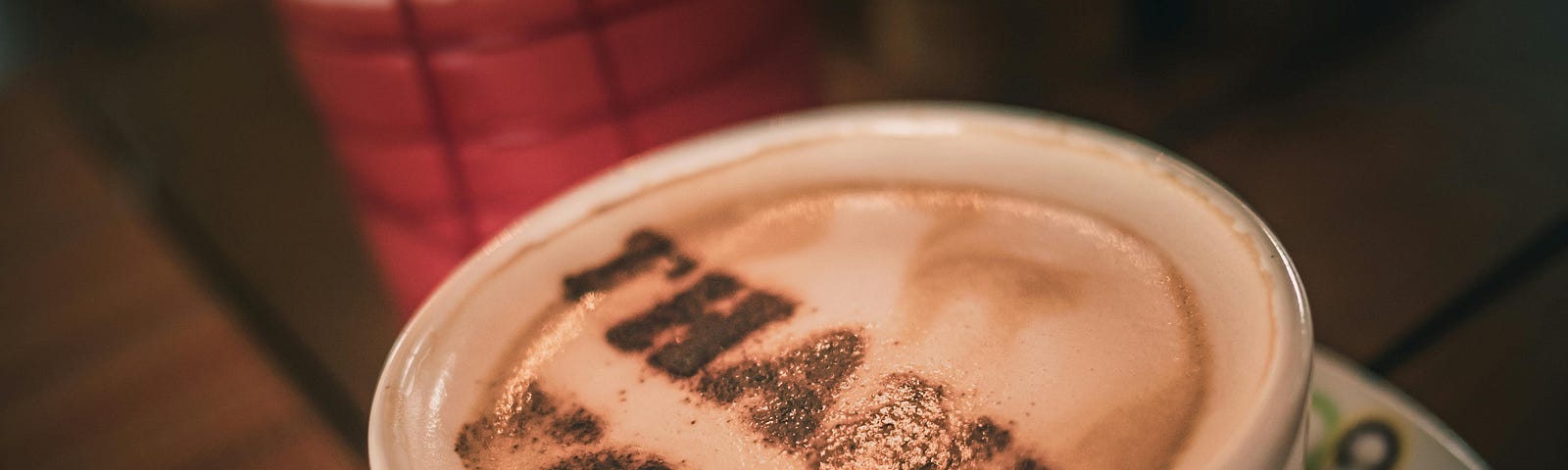 A cup of coffee with Thank you written with chocolate powder as frosting