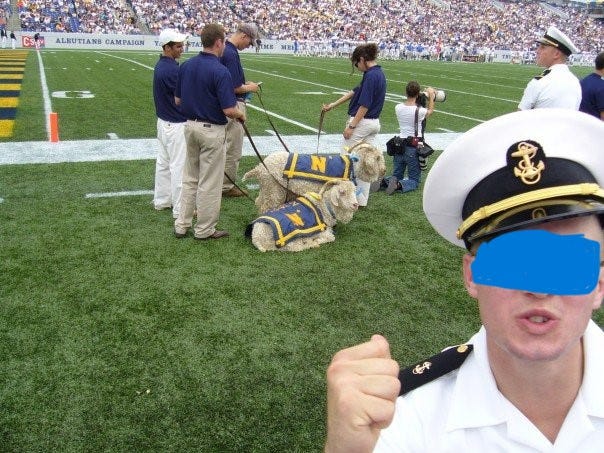 A man in a navy uniform making a fist in the football stadium