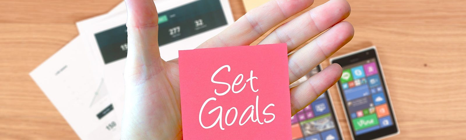 a hand holding a card with “Set goals” written on it