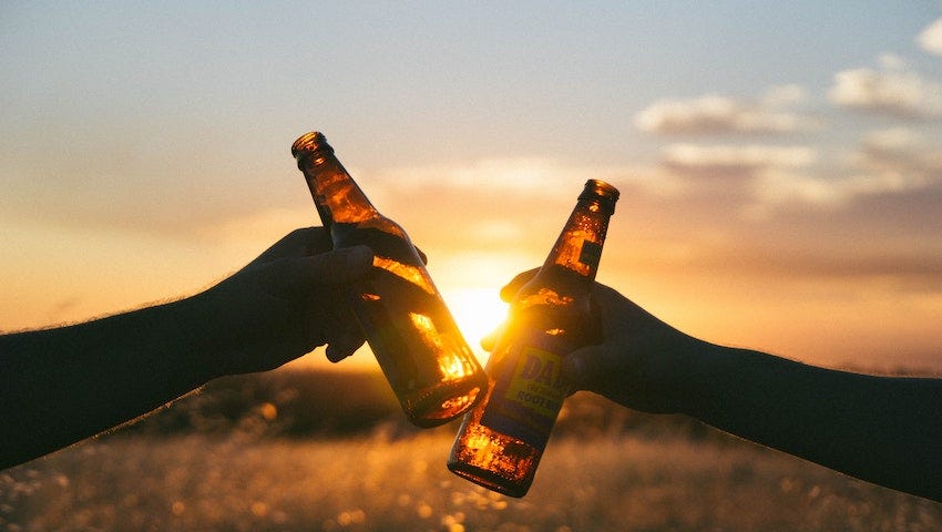 Picture of cheering drinks in front of a sunset