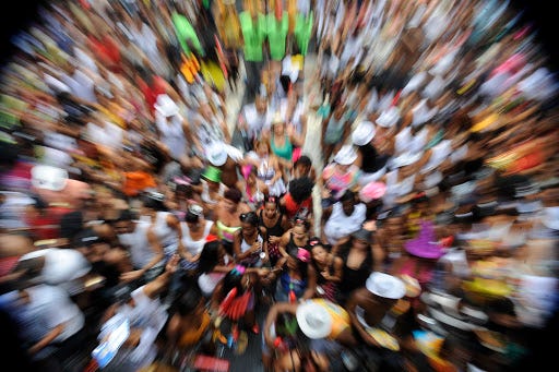 Foto de aglomeração de pessoas em bloco de carnaval. Aparece muitos corpos na imagem, com foco ao centro e desfocada ao redor