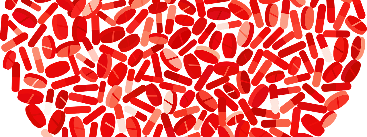 A red heart shape created using pills of different shapes and sizes.