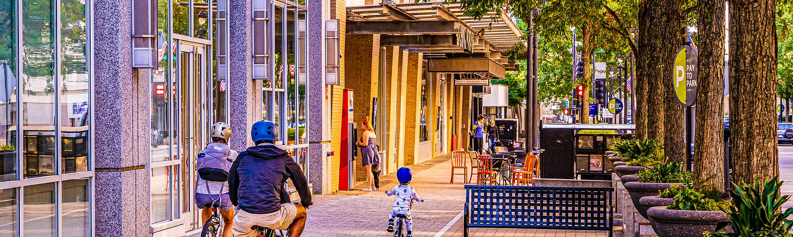 A small boy in pajamas rides his tiny bike downtown