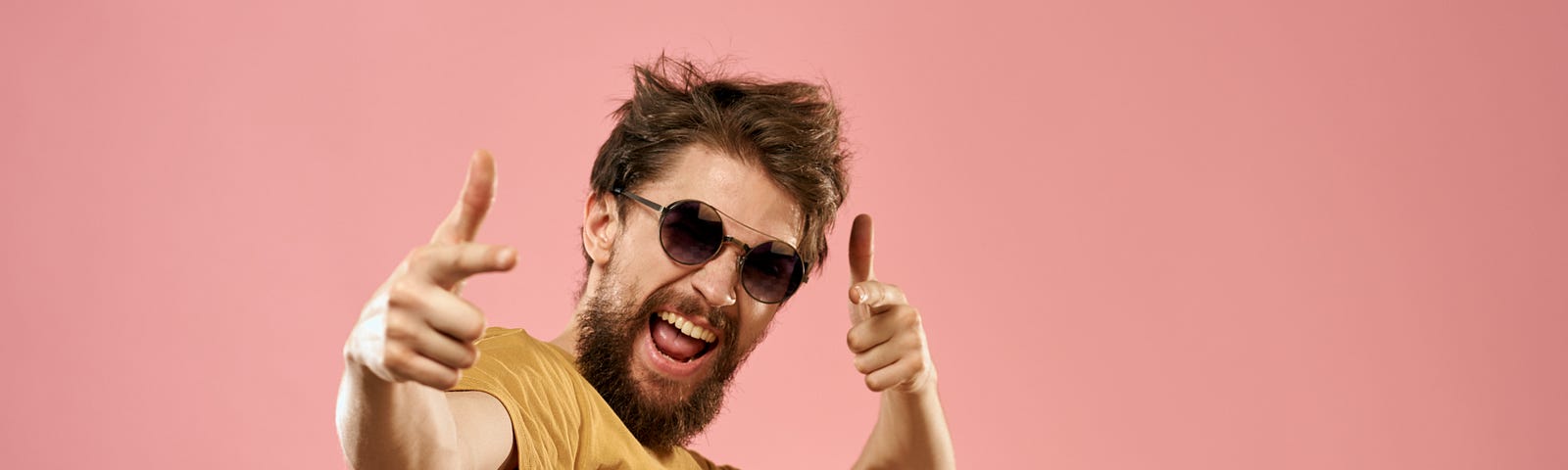 A bearded man wearing sunglasses dancing on pink background