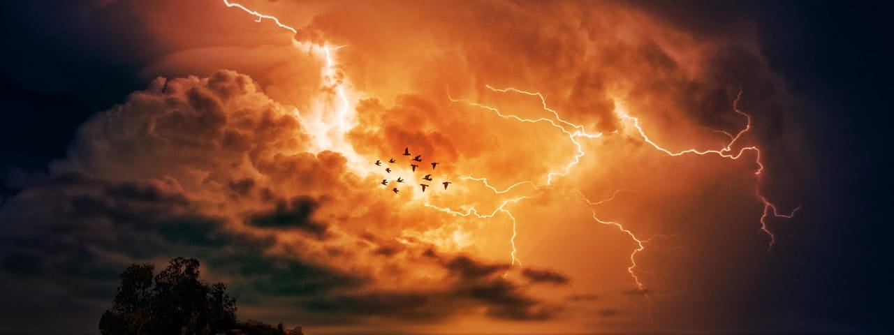 Lightning flashes across an orange sky.