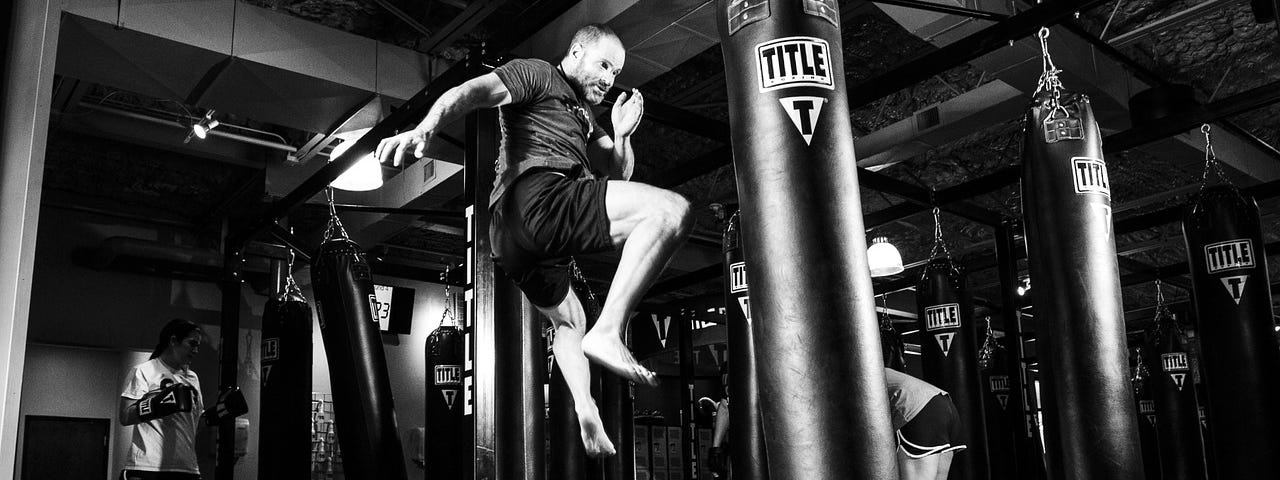 A man practicing his flying knee strike on a punching bag