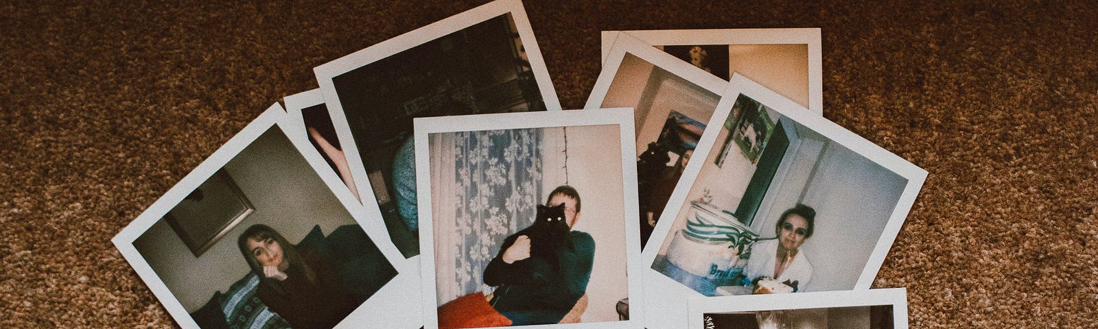 Photo of numerous Polaroid photos arrayed on a brown carpet, with photographer showing own feet in fuzzy pink slippers.