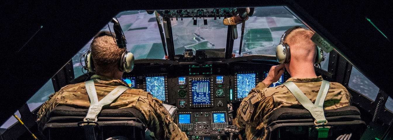 Army personnel practicing flight procedures in a simulator.