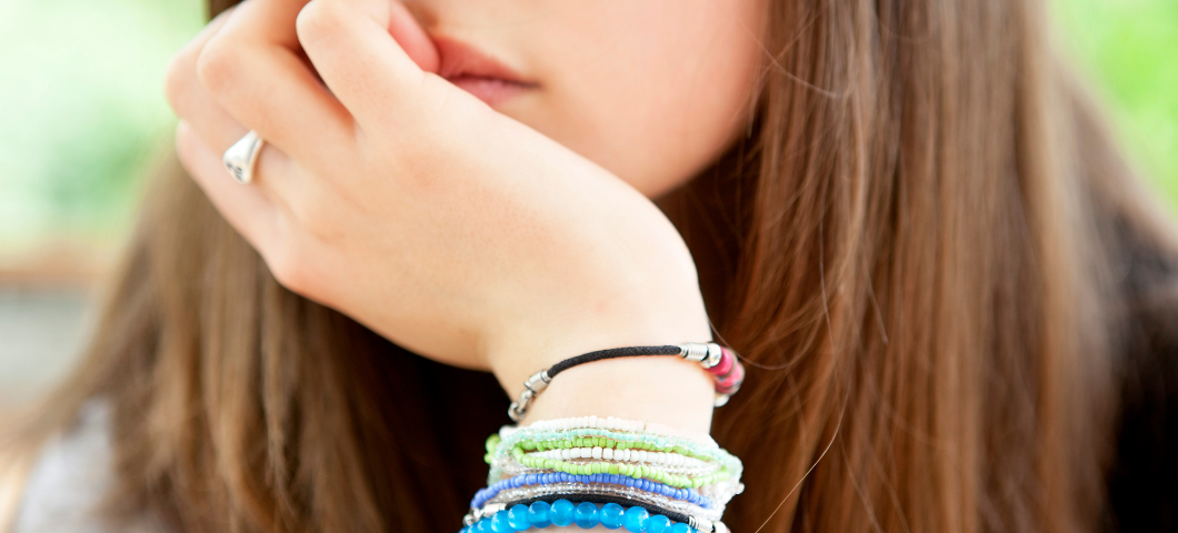 teenage girl with bracelets resting her chin in her hand