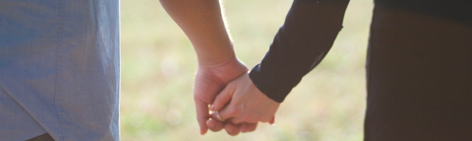 A couple hold hands in the sunlight.